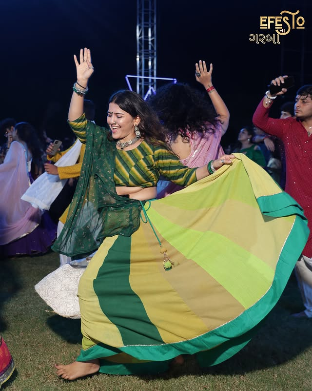 Audience member dancing in green traditional outfit
